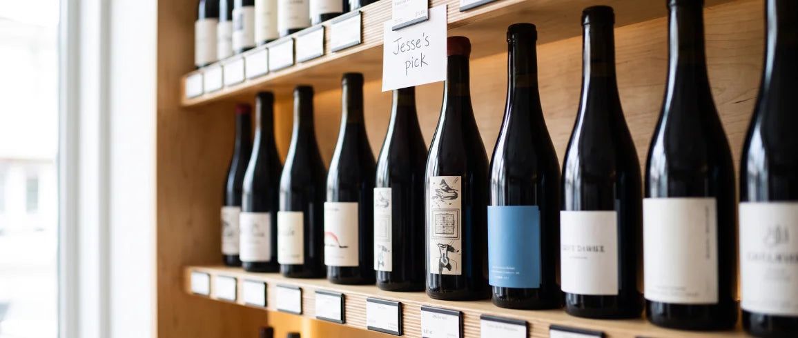 Close shelf of dark bottles and a handwritten card that says Jesse’s pick.